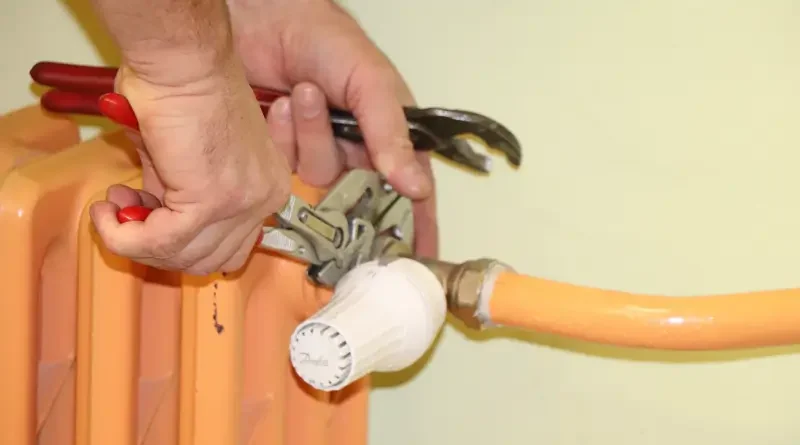 zaměstnanec kovoúdržby  FN instaluje termostatickou hlavici na  uzávěr radiátoru