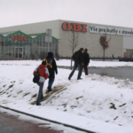 Lidé mířící do nákupního centra z nevhodně umístěné zastávky